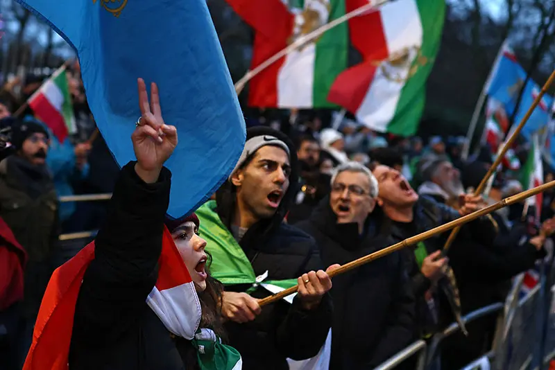 Anti-Iranian regime protesters wave Iranian flags before the 1979 revolution with the Lion and Sun emblems during a gathering outside the Iranian Embassy, central London, on January 9, 2026. (Photo by Henry NICHOLLS / AFP via Getty Images)
